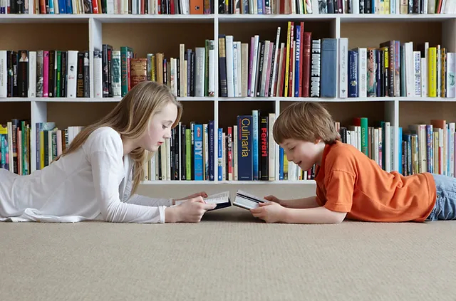 Siblings are reading books on the floor