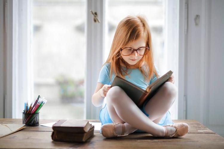 Girl is reading a book near the window