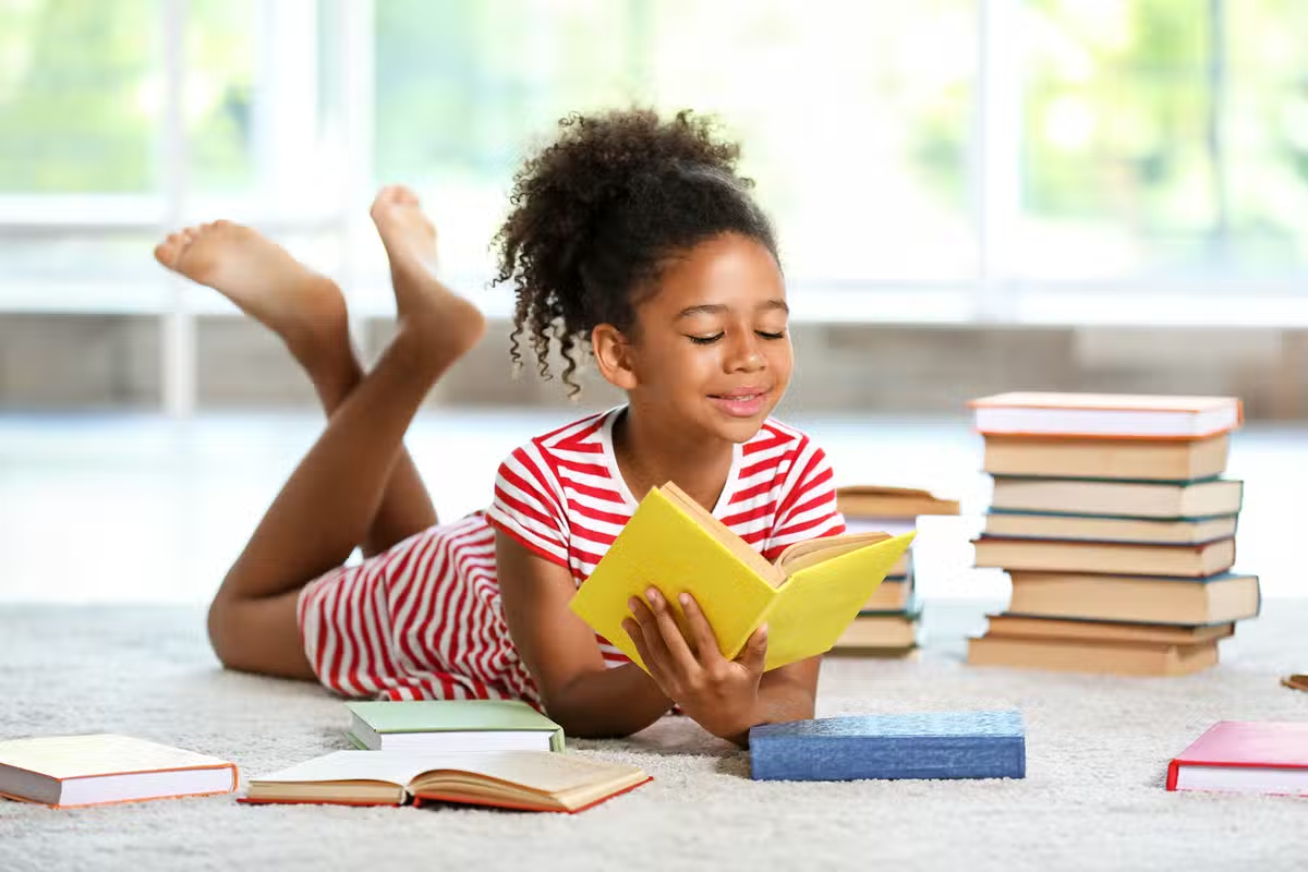 Little girl reading a yellow book